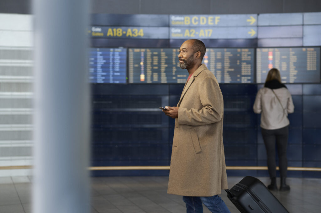 Un homme écoutant les annonces de l'aéroport grâce à ses appareils auditifs ReSound Vivia compatibles Auracast